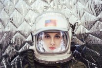 Confident girl wearing old space helmet with usa flag sign on foil background — Stock Photo