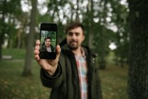 Homme à la forêt avec téléphone portable prenant des photos — Photo de stock