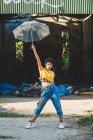 Porträt einer jungen Frau in stylischem Outfit, die an sonnigen Tagen mit durchsichtigem Regenschirm posiert — Stockfoto