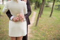 Безликий знімок елегантної нареченої і нареченого чуттєво обіймається в зеленому парку — стокове фото