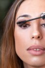 Schnitthände, die Wimperntusche auf Modell auftragen — Stockfoto