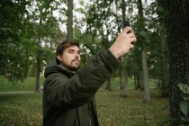 Hombre en el bosque con el teléfono móvil tomar la foto - foto de stock