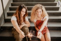 Friends with sparkles on steps — Stock Photo