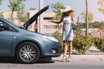 Mädchen steht vor ihrem kaputten Auto — Stockfoto