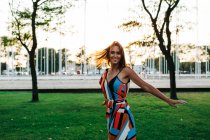 Allegro bruna elegante in abito che gira sul prato verde nel parco urbano — Foto stock