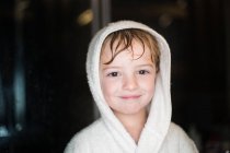 Портрет улыбающегося мальчика с мокрыми волосами в халате — стоковое фото