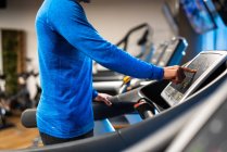 Close-up of athletic man jogging on treadmill in gym — Stock Photo