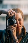 Ritratto di rossa ragazza con trecce scattare foto con fotocamera vintage — Foto stock
