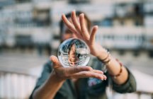 Donna in possesso di sfera di cristallo con riflesso in città — Foto stock