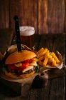 Délicieux burger gastronomique avec couteau sur planche de bois avec bière et frites — Photo de stock