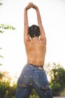 Vista posteriore di fiduciosa donna provocante in jeans in piedi in topless in natura — Foto stock