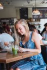 Woman having drink and meal in cafe — Stock Photo