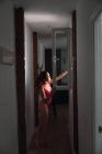 Jovem mulher de fato de banho em pé perto da janela no corredor escuro em casa — Fotografia de Stock