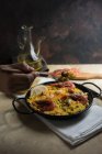 Forchetta umana a mano sulla tradizionale paella marinera spagnola con riso, gamberi, calamari e cozze in padella — Foto stock