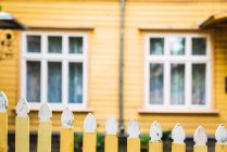 Malerischer Holzzaun, der Hof auf verschwommenem Hintergrund eines gelben Landhauses umgibt — Stockfoto