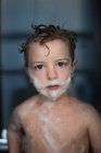 Porträt eines kleinen Jungen mit Schaum auf Gesicht und Körper im Badezimmer — Stockfoto
