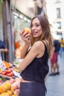 Fröhliche Frau beißt Pfirsich auf Markt — Stockfoto
