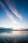 Surface of tranquil blue lake with dramatic sky at sunset — Stock Photo