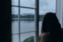 Donna che guarda attraverso la finestra della stanza — Foto stock
