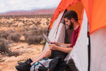 Viaggiatore che utilizza il computer portatile in una tenda — Foto stock