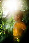 Thoughtful sensual brunette with short hair standing in mist in green vegetation with sunlight — Stock Photo