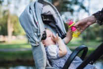 Nahaufnahme weiblicher Hand, die Baby im Kinderwagen im Freien tröstet — Stockfoto