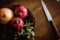 Composizione di cesto con arance, uva e melograni in tavola — Foto stock