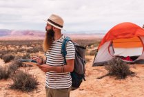 Homem segurando mapa e bússola retro enquanto em pé sobre fundo borrado de majestoso deserto — Fotografia de Stock