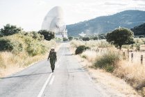 Женщина в костюме космонавта и шлеме идет по дороге в сельской местности — стоковое фото