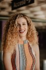 Portrait of smiling curly blond woman with bright lips in striped casual top — Stock Photo