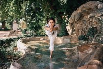 Mulher de pé na água da fonte em pose de árvore ao fazer ioga no parque — Fotografia de Stock