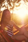 Загорелая женщина на гамаке на солнечной поляне — стоковое фото
