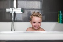 Portrait of smiling little boy sitting in bath — Stock Photo