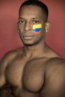 Retrato de homem afro-americano com bandeira colombiana no rosto olhando para a câmera — Fotografia de Stock