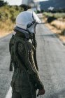 Жіночий астронавт в шоломі і космосі, що стоїть на дорозі в сільській місцевості — стокове фото