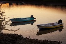 Azzurro e giallo con barche a motore bianche sulla costa con piccole rocce e cespuglio la sera con altri trasporti su sfondo — Foto stock