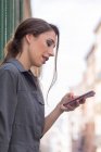 Frau benutzt Smartphone in der Nähe von Haus auf Straße — Stockfoto