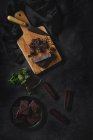 Trozos de chocolate y trozos de menta sobre tabla de madera sobre fondo negro - foto de stock