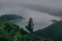 Woman standing on high hill with lake below — Stock Photo