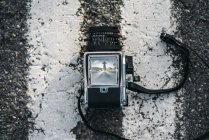 Câmera fotográfica na estrada de asfalto com vista de mulher vestida de astronauta — Fotografia de Stock