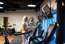 Athletische blonde Frau joggt auf Laufband im Fitnessstudio — Stockfoto