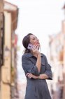 Веселая женщина говорит по смартфону на улице — стоковое фото