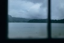 Озеро и гора через окно — стоковое фото