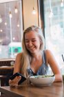 Frau surft im Café mit Smartphone — Stockfoto