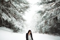 Bella giovane donna in abito elegante guardando lontano mentre in piedi vicino all'albero coperto di neve nella giornata fredda in campagna meravigliosa — Foto stock