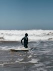 Uomo con tavola da surf a piedi verso l'oceano — Foto stock
