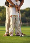 Crop view of one black man teaching another to play golf on green lawn on background of trees at daylight - foto de stock