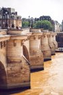 Каменный мост через коричневую реку Сена в Париже на фоне городского пейзажа — стоковое фото