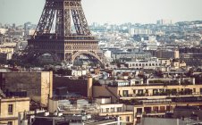 Porão da Torre Eiffel em pé entre os edifícios no fundo da paisagem urbana em Paris — Fotografia de Stock
