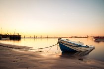 Приручений човен на березі зі спокійною водою — стокове фото